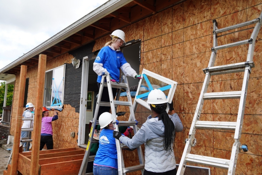 Volunteers installing windows on a house construction site