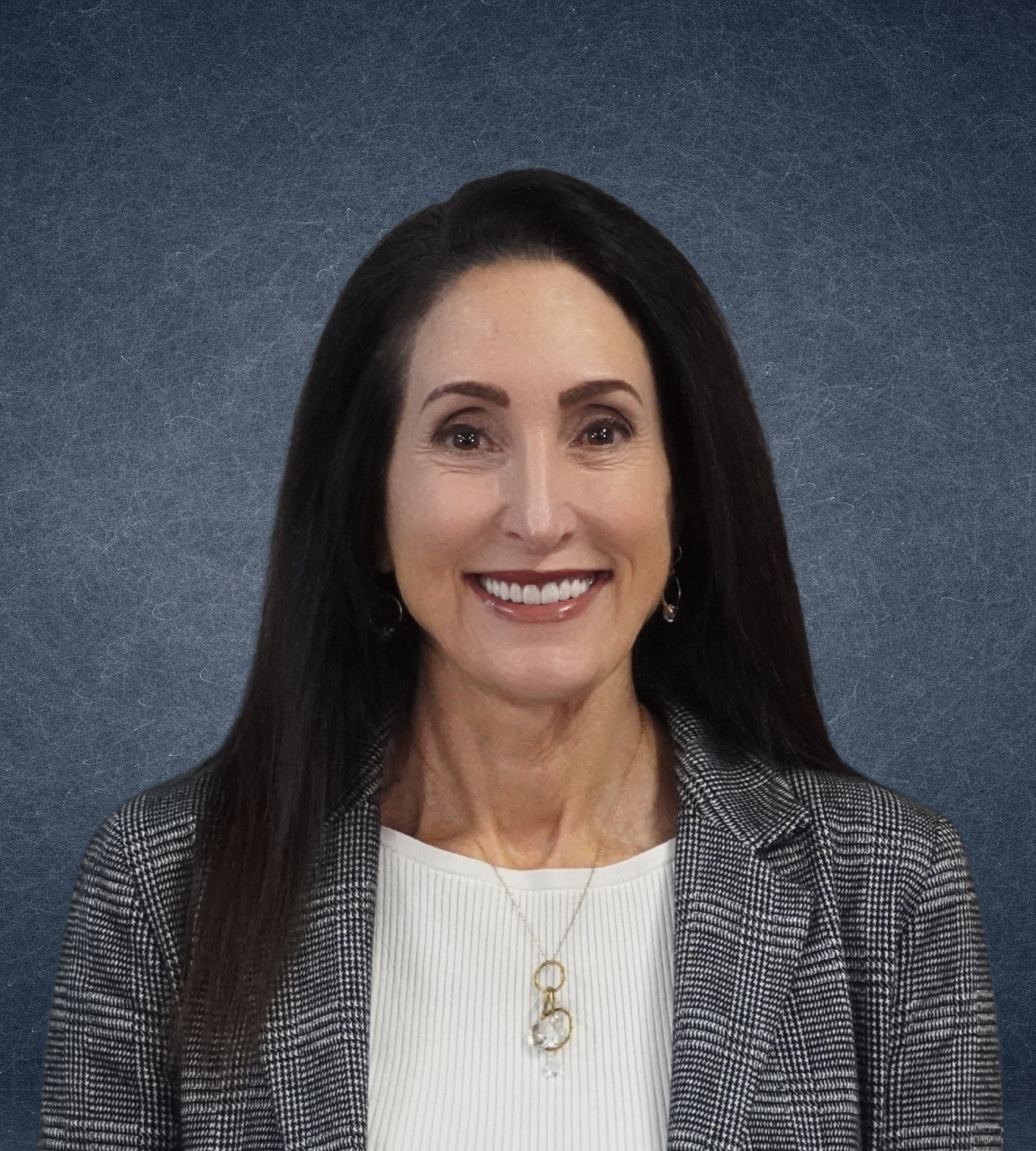 Smiling woman in business attire with long hair against a textured gray background