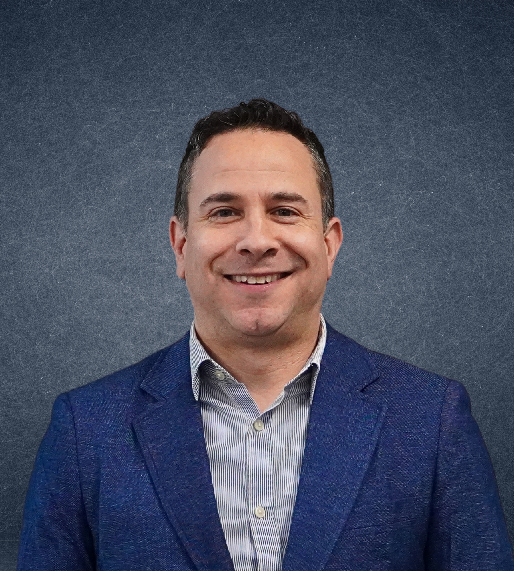 Smiling man in a blue suit jacket with a textured gray background