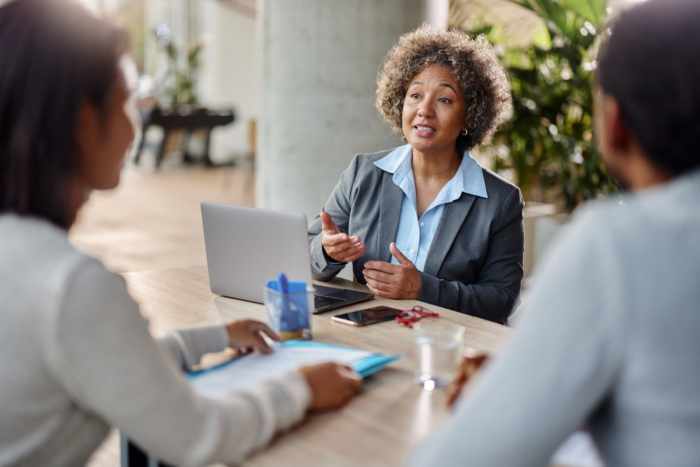 Businesswoman leading a meeting with colleagues at a table in a modern office setting