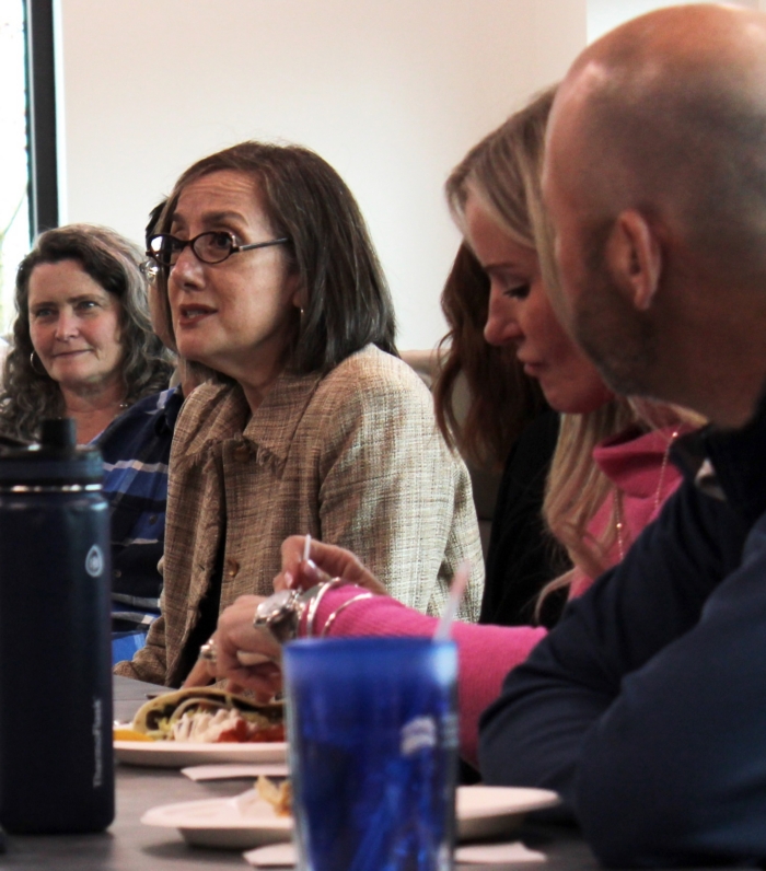 People having a discussion at a dining table eating lunch together