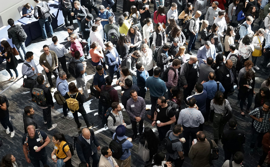 Large group of people networking at a conference event in a crowded indoor space
