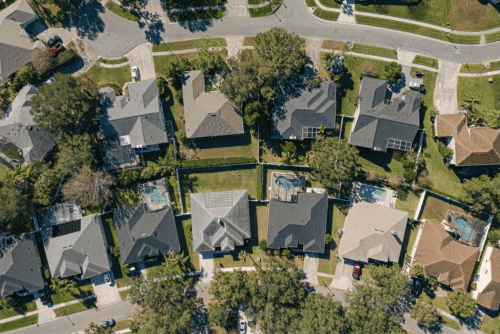 Aerial view of suburban neighborhood with houses and backyards on a sunny day